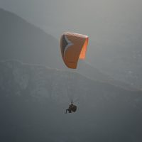 person in orange parachute over white clouds during daytime