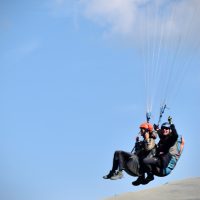 man in black jacket and orange helmet riding on red and black parachute